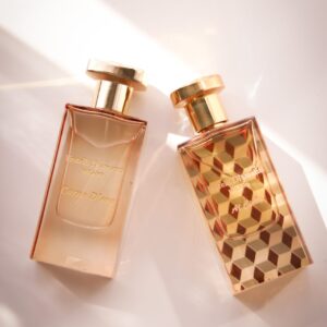 Two elegant perfume bottles with geometric designs in a bright setting.