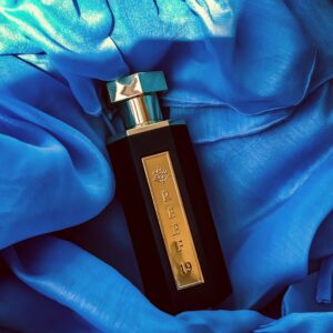 A sleek perfume bottle rests elegantly on luxurious blue satin fabric.