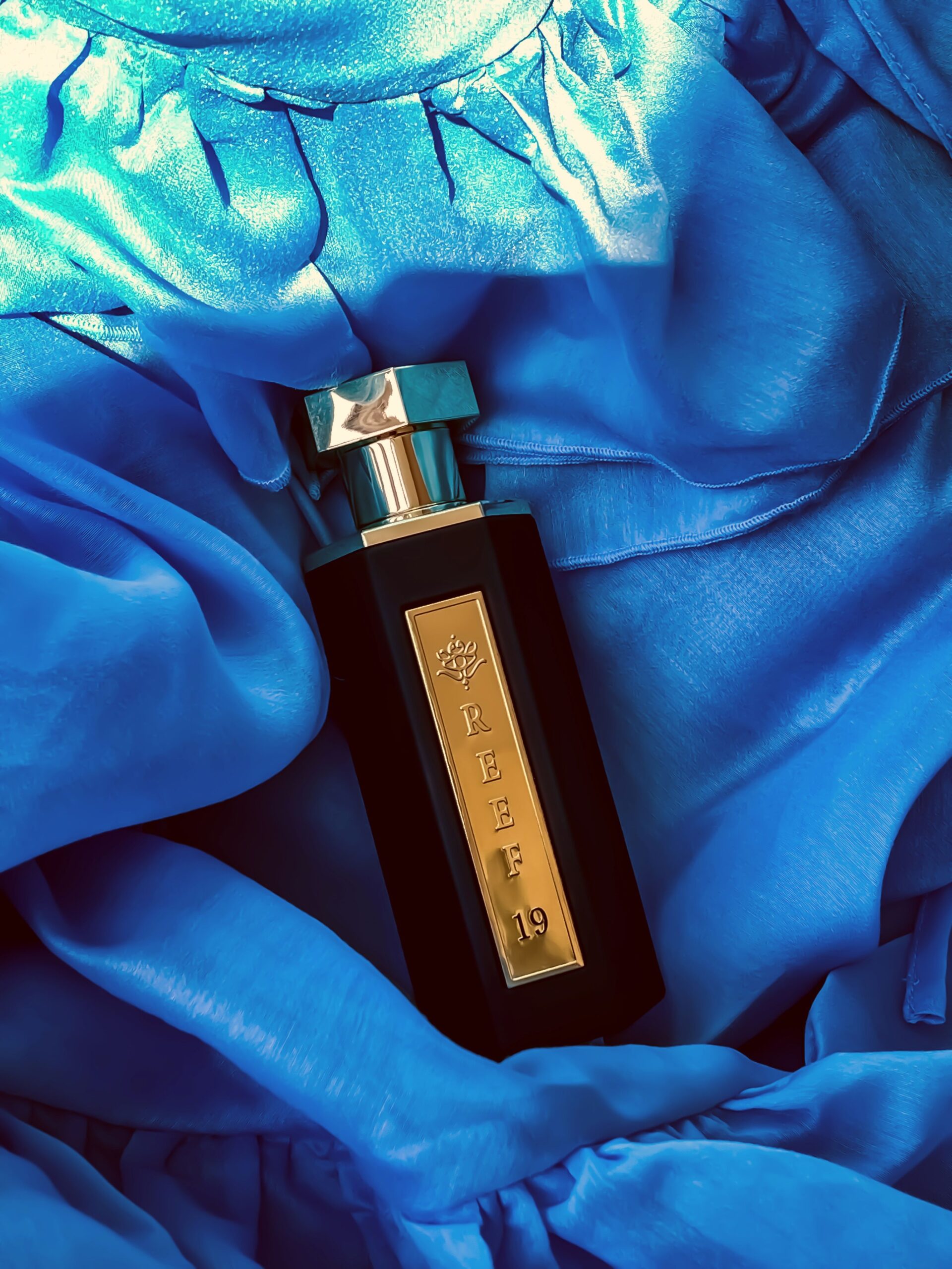pexels photo 32566125 32566125 A sleek perfume bottle rests elegantly on luxurious blue satin fabric.