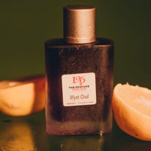 Elegant Myst Oud perfume bottle surrounded by fresh citrus for a luxurious aroma shot.